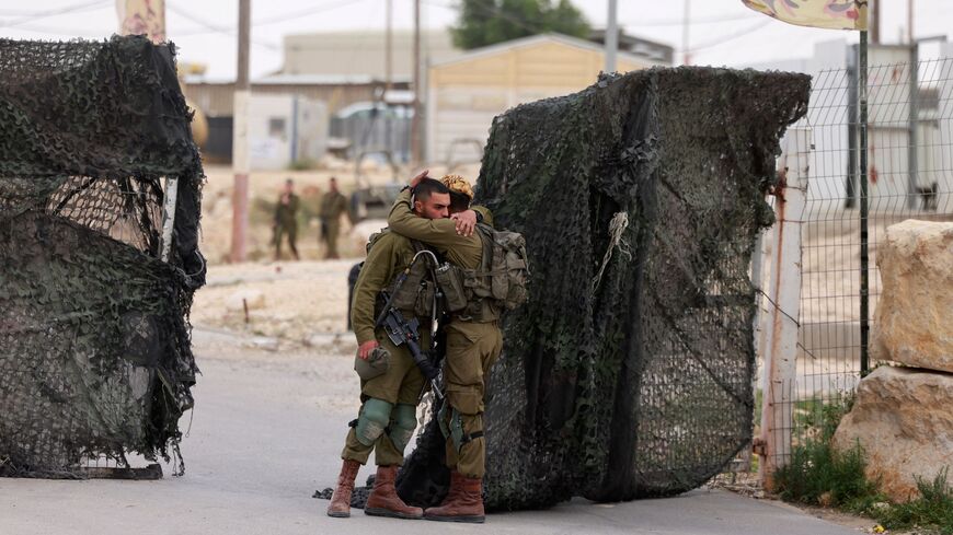 Israeli soldiers console one another outside the Mount Harif military base.